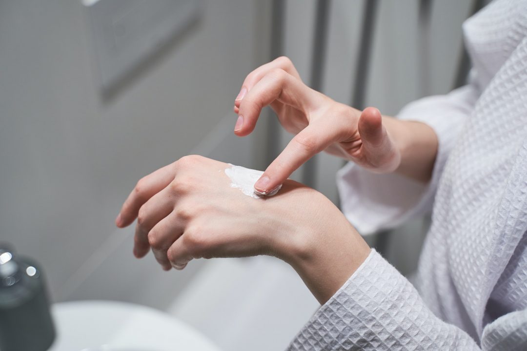 woman rubbing a moisturizer to her skin